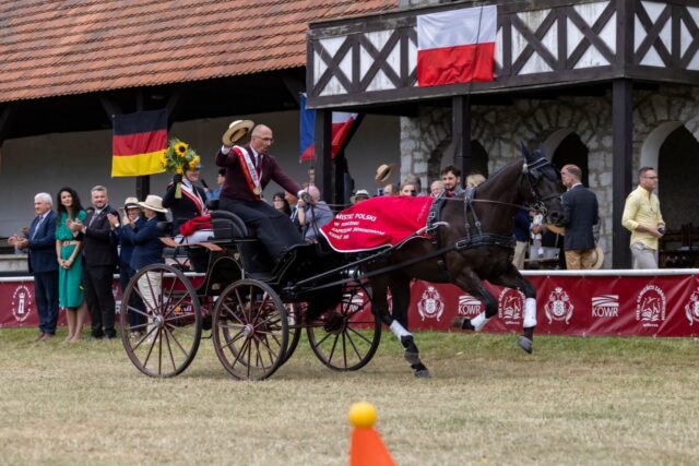 Mistrz Polski w powożeniu zaprzęgami jednokonnymi Książ 2026 machający kapeluszem z bryczki podczas rundy honorowej